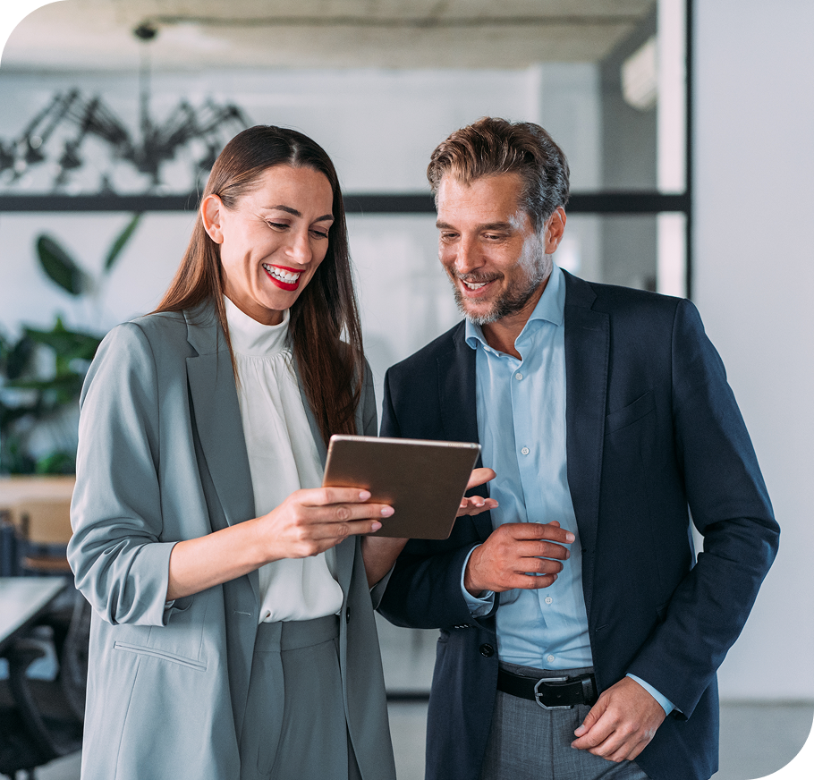 smiling man & woman in a business attire looking at a tablet